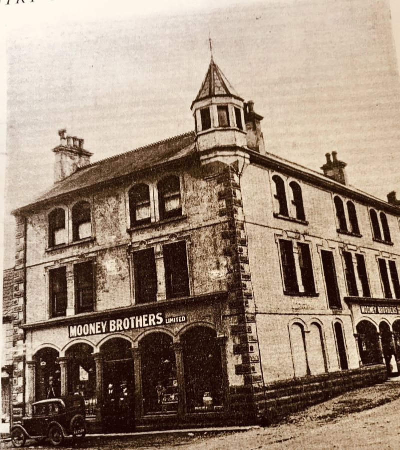 An old photograph of the Mooney Brothers Limited premises, a grand turreted building in Upper Square, Castlewellan.